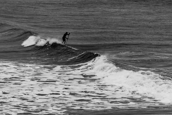 Surfer hält Ruder im Neoprenanzug und verhandelt Wellen auf Reifen — Stockfoto