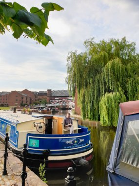 Castlefield 'ın güzel manzarası, Uk' un ilk şehir mirası parkı. Dar bir teknede oturan bir adam kitap okuyarak rahatlıyor..
