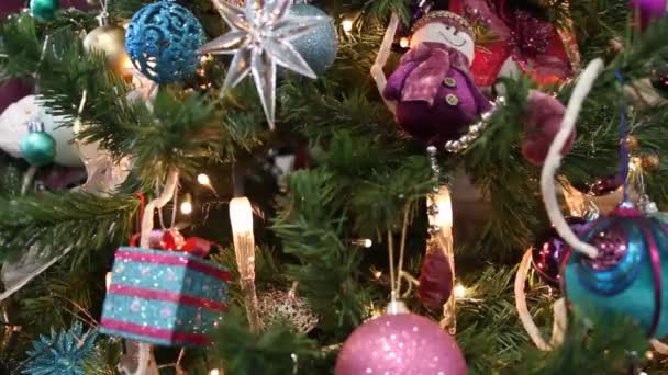 星と紫のテーマで飾られたクリスマスツリーには 紫色の雪だるまの装飾ボールとキャンドルライトが見えます — ストック動画