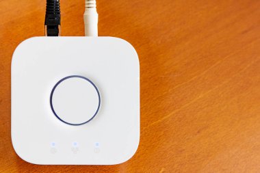 Telif uzaylı kahverengi ahşap masaüstünde ev otomasyonu için beyazlı Smart Home Hub.