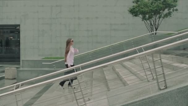 Mujer de negocios con el teléfono está en las escaleras en medio del centro de negocios — Vídeos de Stock