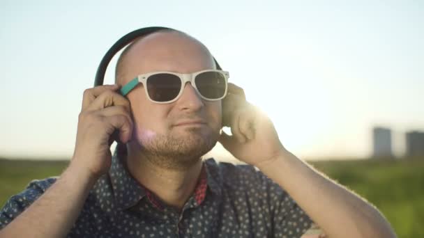 Mann setzt Kopfhörer auf und hört Musik — Stockvideo