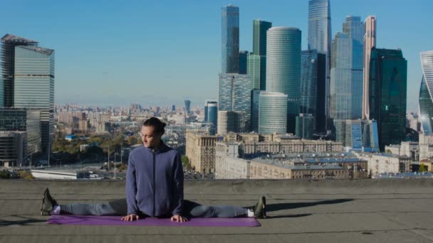 Man stretching on the roof against the backdrop of the city — Stockvideo