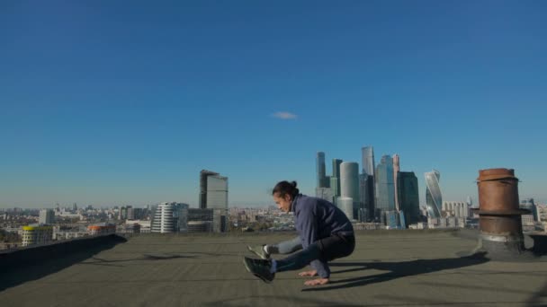 Człowiek, rozciągający się na dachu na tle miasta — Wideo stockowe