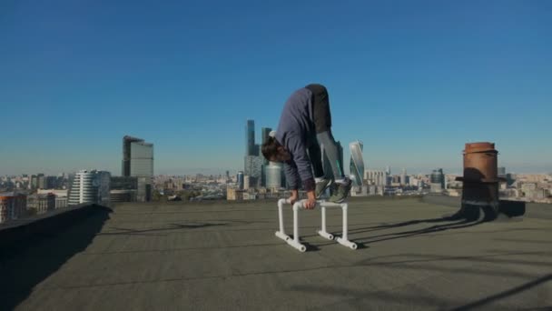 Mann breitet sich vor der Kulisse der Stadt auf dem Dach aus — Stockvideo
