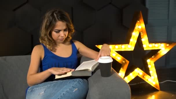 Menina sentada no sofá e livro de leitura — Vídeo de Stock