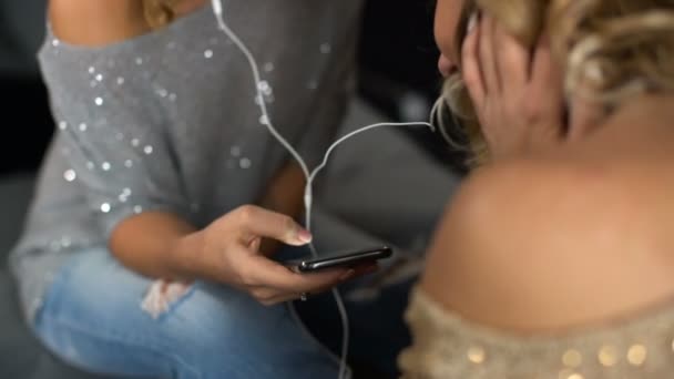 Le amiche felici ascoltano la musica dal telefono e ridono — Video Stock