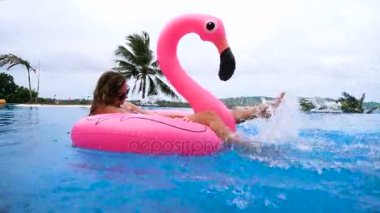 Hindistan cevizi içme ve pembe bir şişme şişme bir yüzme havuzunda - güzel model mükemmel şekiller egzotik bir tatil beldesine soğutma ile rahatlatıcı güzel genç kadın