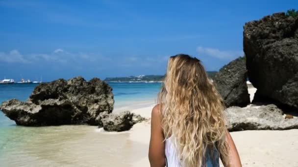 Jeune fille blonde court le long de la plage blanche avec des rochers et souriant. Je me sens libre . — Video