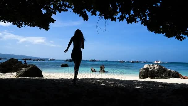 Young blonde girl runs along the white beach with rocks and smiling. I feel free. — Stock Video