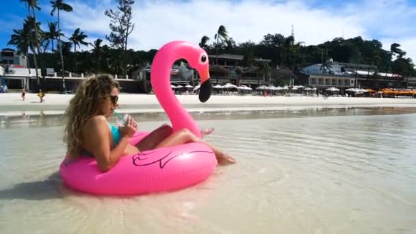 セクシーな女の子は、澄んだ水と美しい白いビーチに膨脹可能なマットレスに浮かぶ — ストック動画