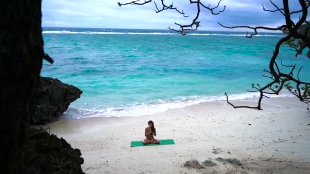 Девушка на пляже практикует йогу — стоковое видео