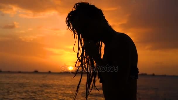 Sexy dívka s mokrými vlasy, oblečen v plavkách pózuje na sunset beach — Stock video