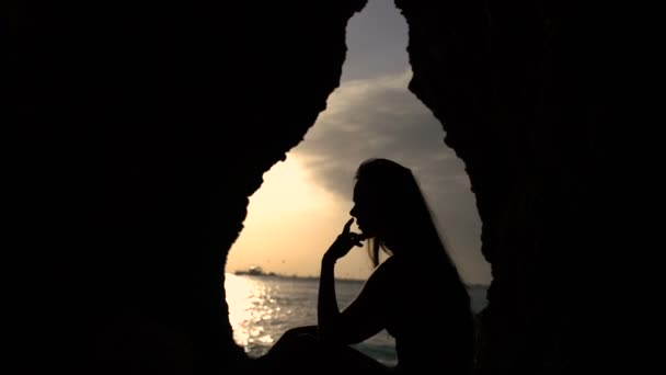 Menina em silhueta ao pôr do sol nas pedras — Vídeo de Stock