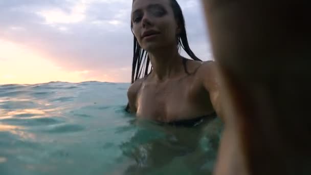 Сексуальна дівчина під час заходу сонця занурюється під воду з камерою — стокове відео