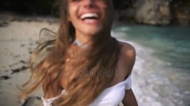 Güzel gülümseme ve sahilde gülüyor ve çalışan uzun saçlı seksi kız