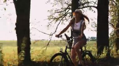 Genç sarışın kız pantolon retro Bisiklet alanında yolda gidiyor