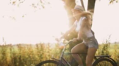 Genç sarışın kız pantolon retro Bisiklet alanında yolda gidiyor