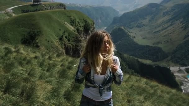 Uma jovem de saia com uma mochila vai para o topo das montanhas com um belo cabelo. Movimento lento — Vídeo de Stock