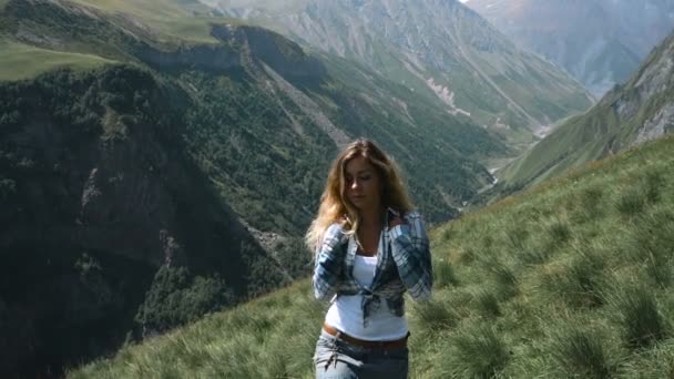 배낭 스커트에 젊은 여자는 아름 다운 머리를 가진 산의 정상에 간다. 슬로우 모션 — 비디오