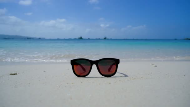 Beautiful glasses are lying on the beach on the background of the sea. — Stock Video