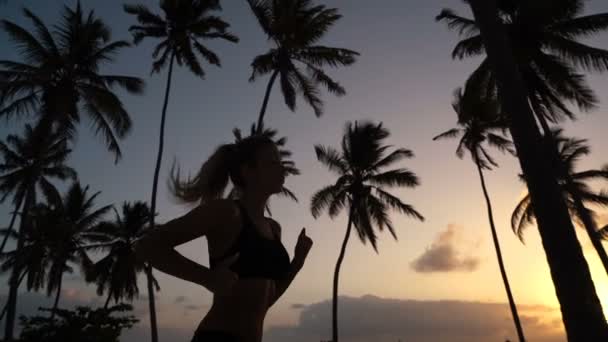 The girl runs around in the morning in the palm trees at dawn — Stock Video