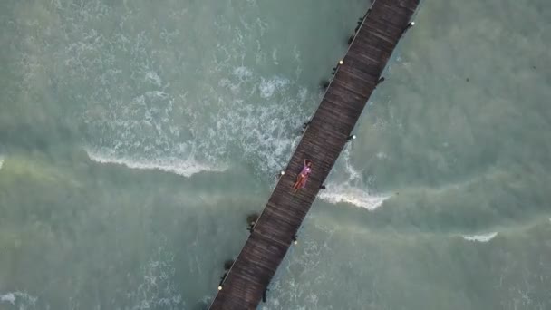 Letecká: dívka leží na dřevěný most. Vlny na pozadí — Stock video