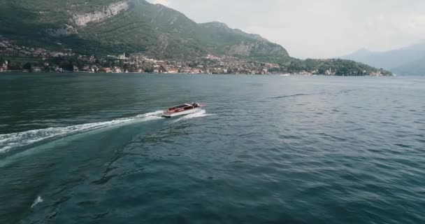 Viejo barco de caoba a motor flota en el lago de Como con el telón de fondo de las montañas — Vídeo de stock