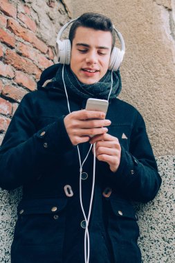Genç adam akıllı telefon headpho ile müzik dinlemek gülümseyen