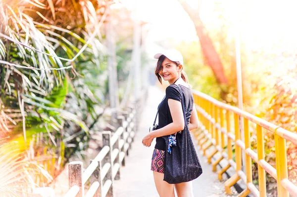 Retrato de una hermosa joven sonriente, Mujer joven atractiva disfrutando de su tiempo al aire libre en la pasarela en el parque con puesta de sol —  Fotos de Stock