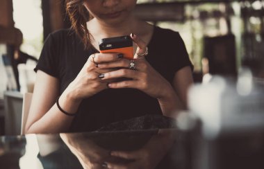 Genç bir kadın akıllı telefonunu kullanarak süre kamera ile restoran bir masada oturuyor