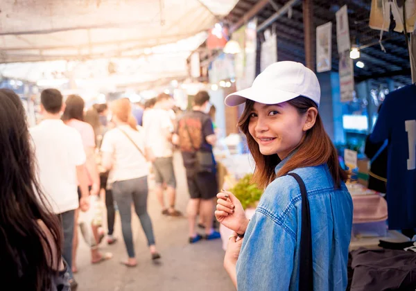 Μια νεαρή γυναίκα που φοράει ένα καπέλο είναι το περπάτημα στους δρόμους αγορά από μια ασιατική χώρα, Ταϊλάνδη — Φωτογραφία Αρχείου