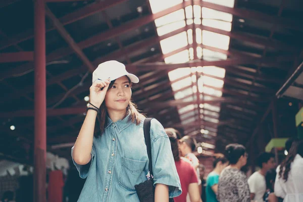 Uma jovem mulher usando um chapéu está andando nas ruas do mercado de um país asiático, Tailândia — Fotografia de Stock