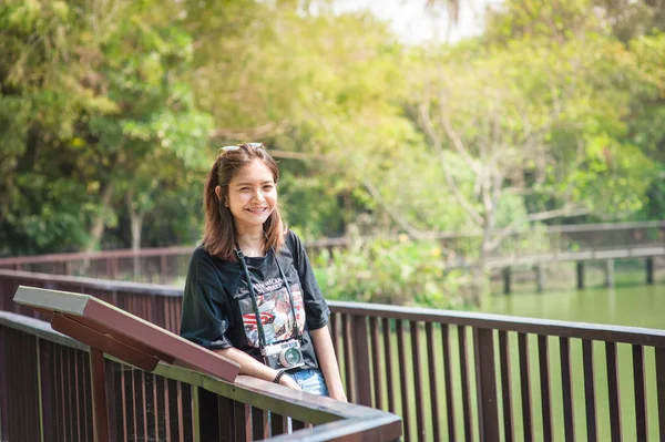 Ritratto di una bella giovane ragazza sorridente, Giovane donna attraente che si gode il suo tempo all'aperto sulla passerella nel parco — Foto Stock