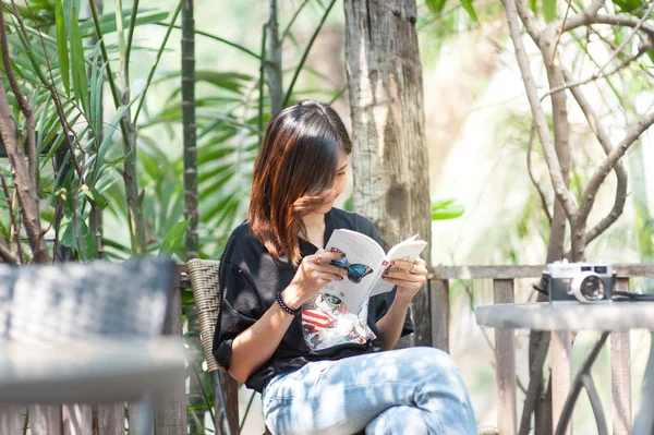 Jovem mulher asiática relaxar com a leitura de um livro e câmera filme no café, ao ar livre estilo de vida & vintage tom de imagem — Fotografia de Stock