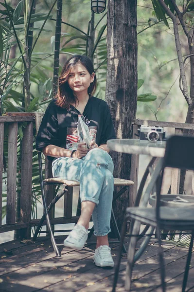 Jovem mulher asiática relaxar com a leitura de um livro e câmera filme no café, ao ar livre estilo de vida & vintage tom de imagem — Fotografia de Stock