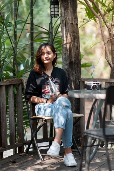 Giovane donna asiatica rilassarsi con la lettura di un libro e pellicola della macchina fotografica in caffè, Stile di vita all'aperto e foto tono vintage — Foto Stock