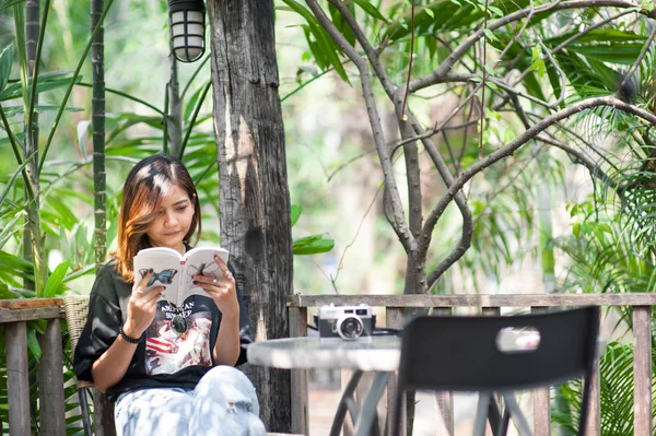 Giovane donna asiatica rilassarsi con la lettura di un libro e pellicola della macchina fotografica in caffè, Stile di vita all'aperto e foto tono vintage — Foto Stock