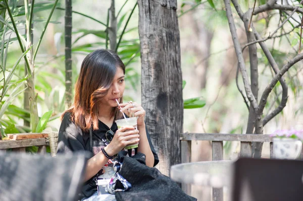 Menina asiática bonita está chupando chá verde em uma cafeteria, feliz em relaxar . — Fotografia de Stock