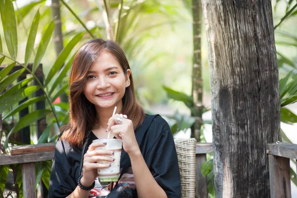 美しいアジアの女の子は、リラックスさせてコーヒー ショップで緑茶を吸っています。. — ストック写真