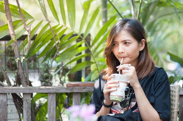 Hermosa chica asiática está chupando té verde en una cafetería, feliz de relajarse . —  Fotos de Stock