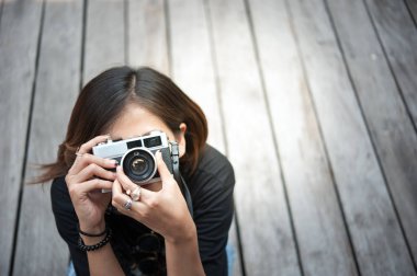 Ahşap floorof Şehir Parkı, güzel kız eski kamera fotoğrafı üzerinde retro film kamerası ile fotoğraf çekmek hipster kadın