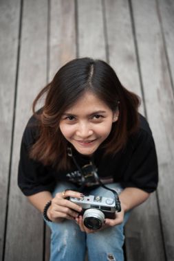 Ahşap floorof Şehir Parkı, güzel kız eski kamera fotoğrafı üzerinde retro film kamerası ile fotoğraf çekmek hipster kadın