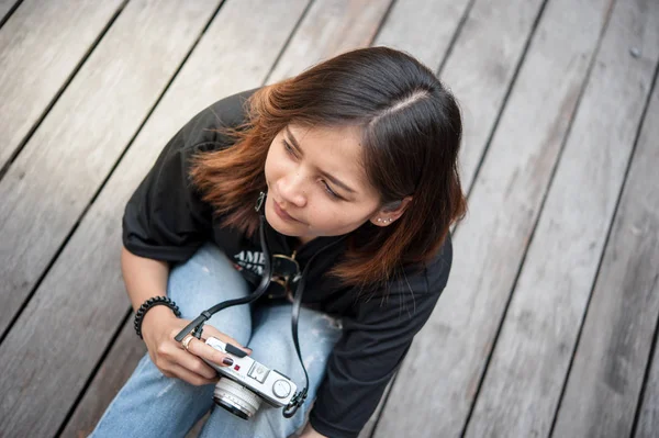 Hipster mujer tomando fotos con cámara de película retro en el suelo de madera del parque de la ciudad, hermosa chica fotografiada en la cámara vieja —  Fotos de Stock