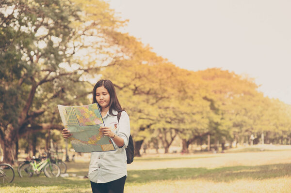 Women traveler with backpack checks map to find directions in the park of Thailand,active people lifestyle