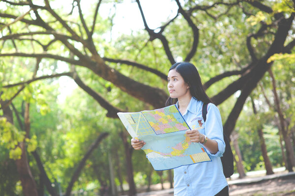 Women traveler with backpack checks map to find directions in the park of Thailand,active people lifestyle