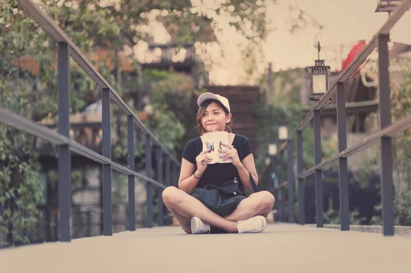 Hipster mujer adolescente sentado disfrutar de la lectura de libro en el muelle. Joven mujer lectura libro concepto, retro filtro tonificado . —  Fotos de Stock