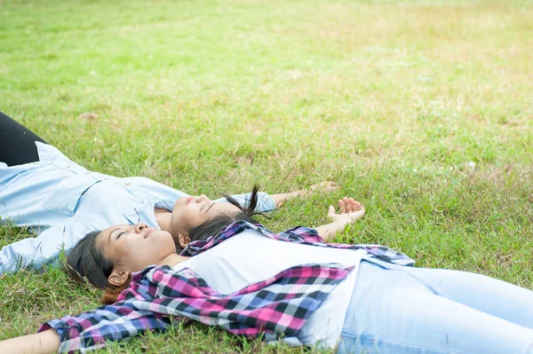 Dois Jovem Mulher, Menina bonita é relaxante deitado na grama no parque — Fotografia de Stock