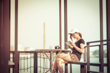 Şık öğrenci kız Tayland river tarafında kitapla rahatlayın. Açık hava yaşam tarzı resim