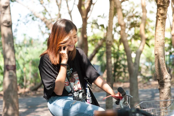 Όμορφο κορίτσι σε ένα ποδήλατο που μιλούν στο κινητό τηλέφωνο στο πάρκο — Φωτογραφία Αρχείου